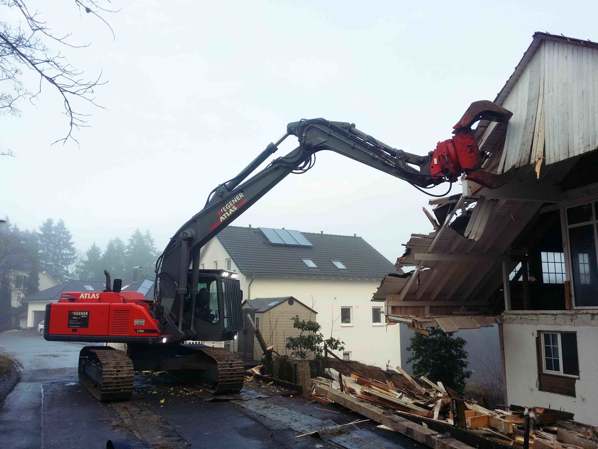 WEGENER Abbruchbagger mit Sortiergreifer trägt das Dachgeschoss der abzubrechenden Wohnhaushälfte ab
