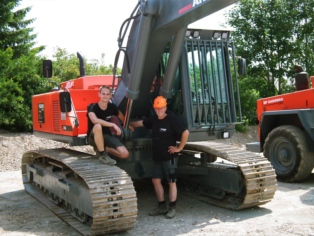 Wilfried und Steve Wegener gemeinsam vor ihrem roten ATLAS-Kettenbagger
